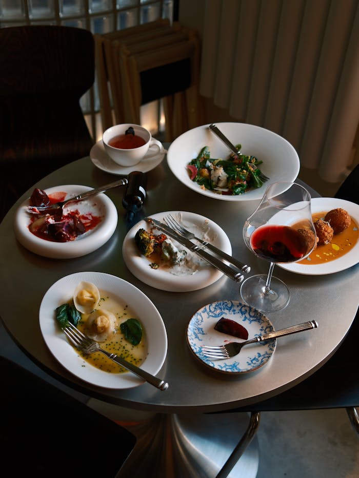 A collection of gourmet dishes and wine on a stylish round table.